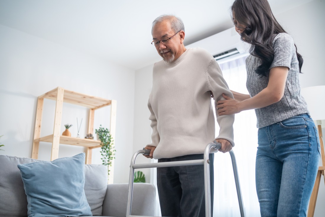 A family caregiver helps an aging relative use a walker
