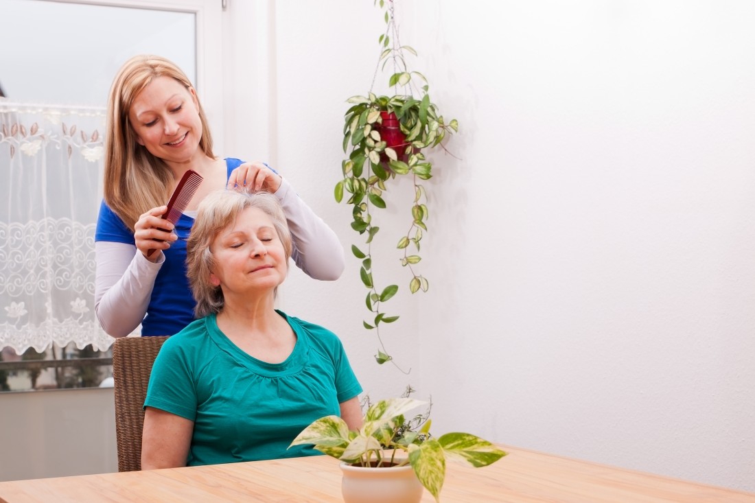 A family caregiver brushes the hair of an aging relative